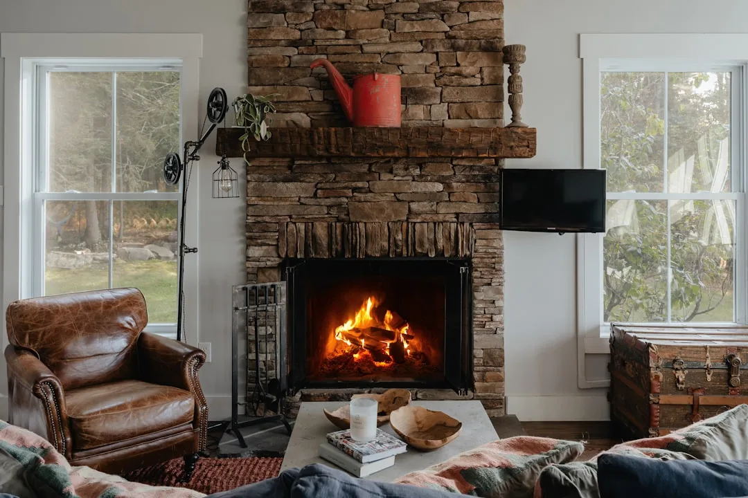 Rustic stone fireplace with wood mantel and built-in surround in cozy living room with leather armchair
