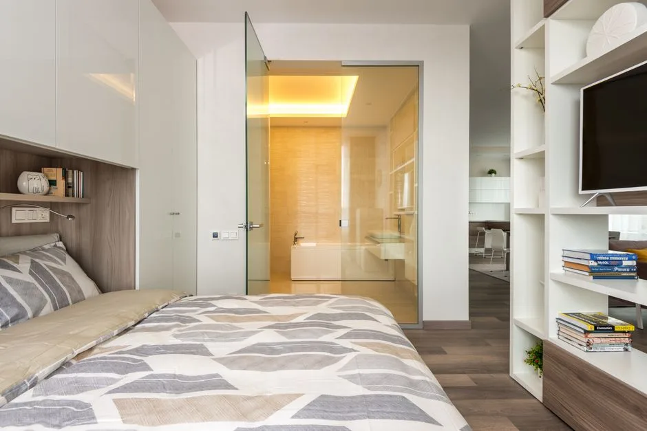 Modern master bedroom with glass door opening directly into ensuite bathroom showing integrated bedroom-bathroom layout