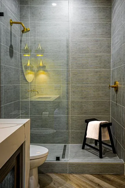 Large format gray tiles in small bathroom shower demonstrating how oversized tile scale creates spacious visual effect