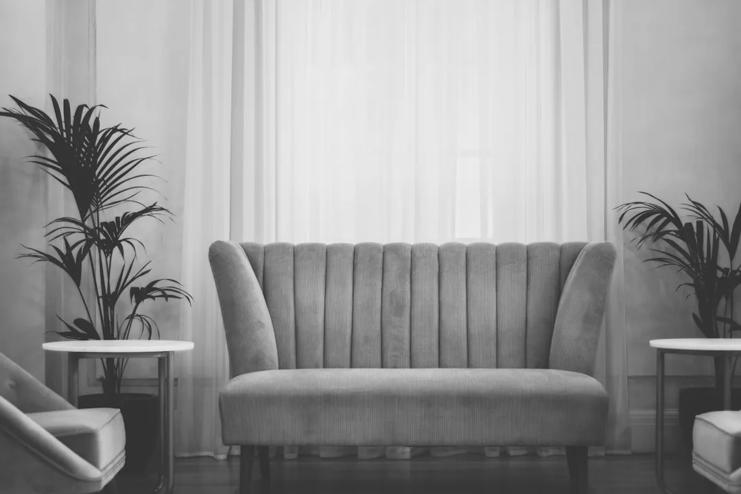 Channel-tufted gray loveseat flanked by armchairs