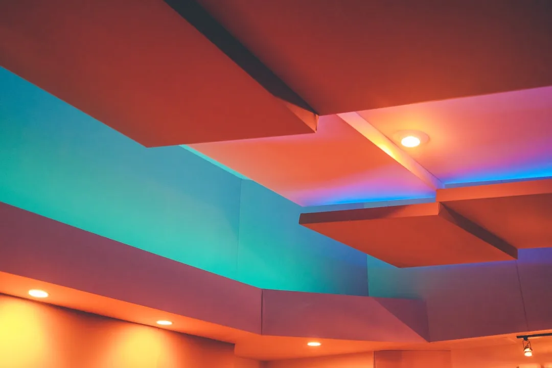 Architectural ceiling with colorful LED lighting showing teal, blue and orange color transitions on wall and ceiling pan