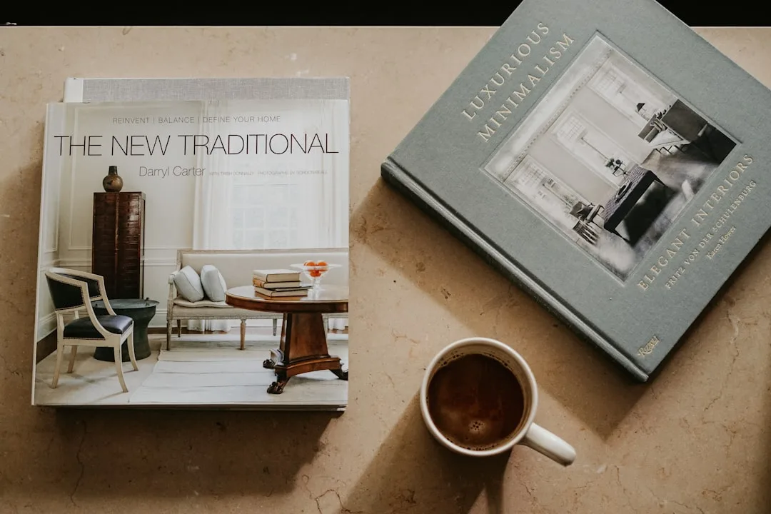 Two interior design hardcover books styled on marble surface beside a cup of coffee as decorative home elements