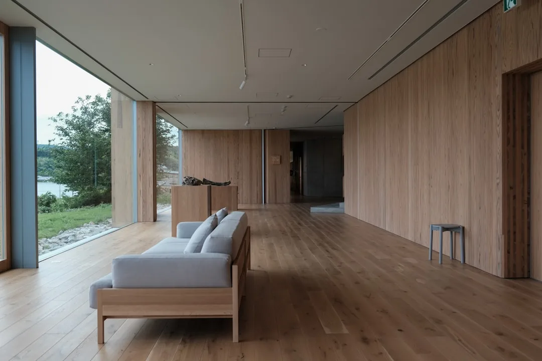Minimalist interior with wide-plank light oak wood floors and matching wood-paneled walls in modern open space