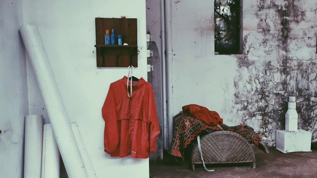 Red jacket hanging on wall with mold and humidity damage on deteriorating walls in storage area