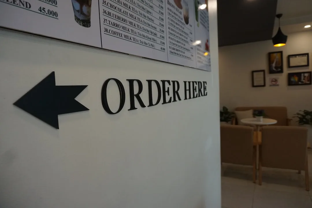 Order Here sign with directional arrow on white partition wall in modern cafe interior