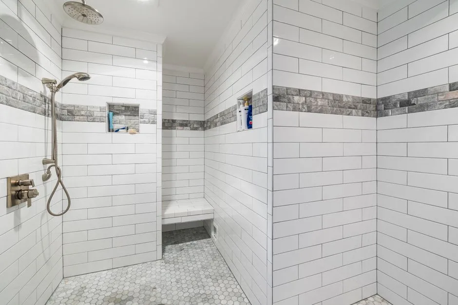Large walk-in shower with white subway tiles, hexagon floor, built-in niches, bench seat, and rainfall showerhead