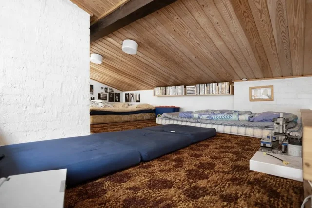 Converted attic sleeping space with sloped wood ce