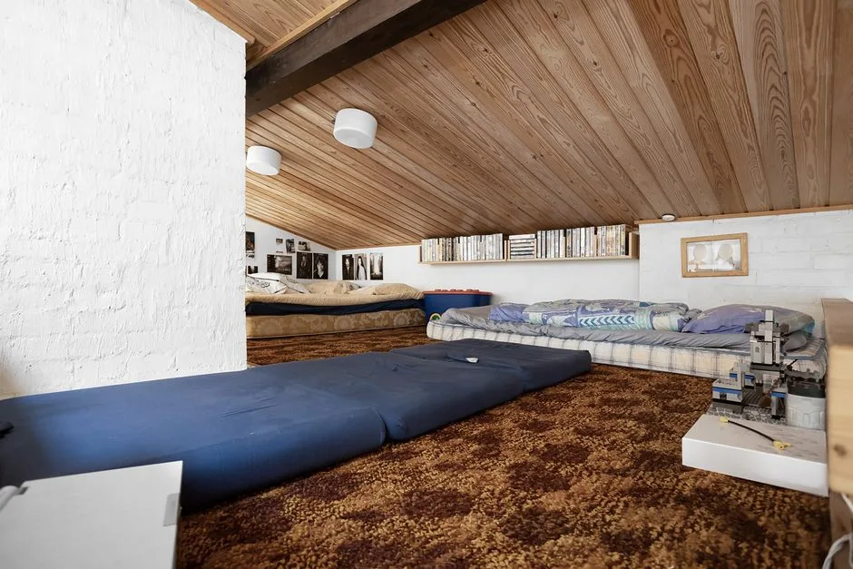 Converted attic sleeping space with sloped wood ce