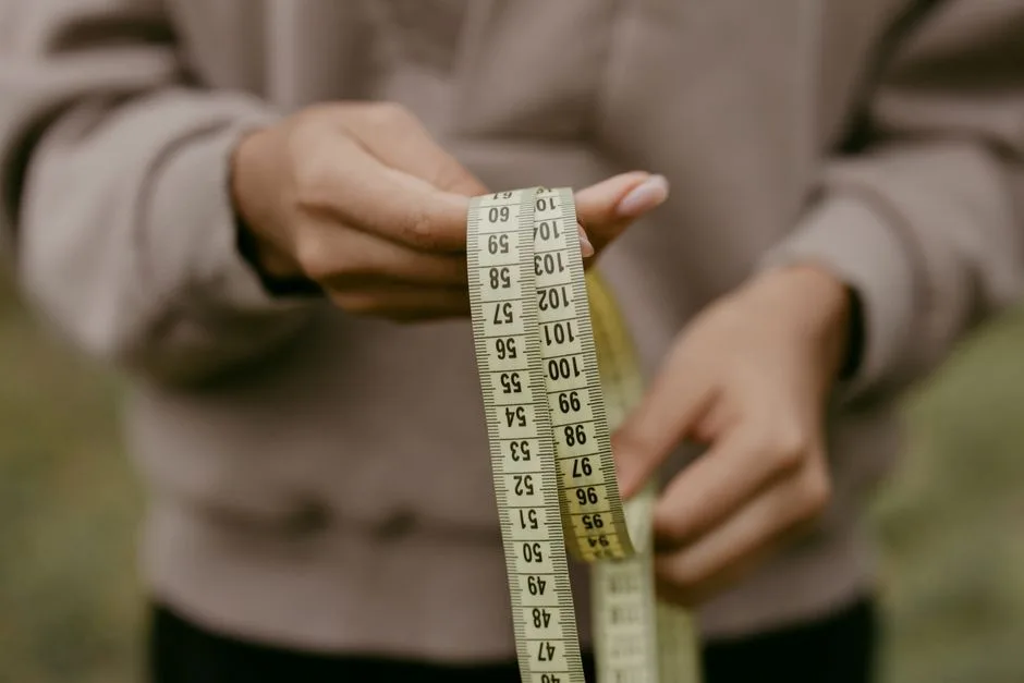 Hands holding a flexible measuring tape showing centimeter markings, illustrating how to measure clearance before buying