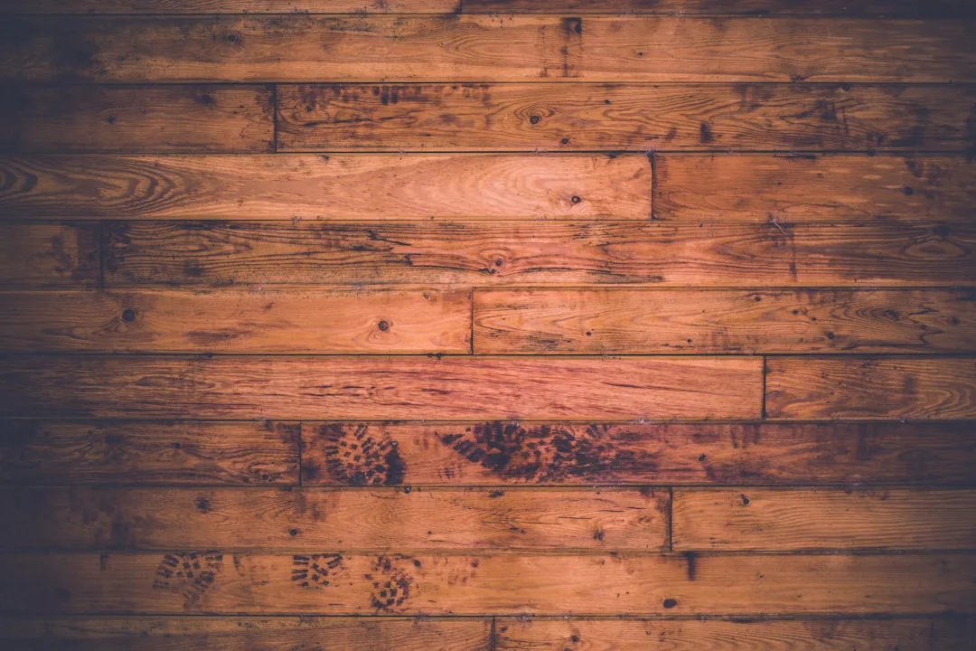 Rustic hardwood floor with natural wood grain, knots, and warm brown tones showing varied plank colors