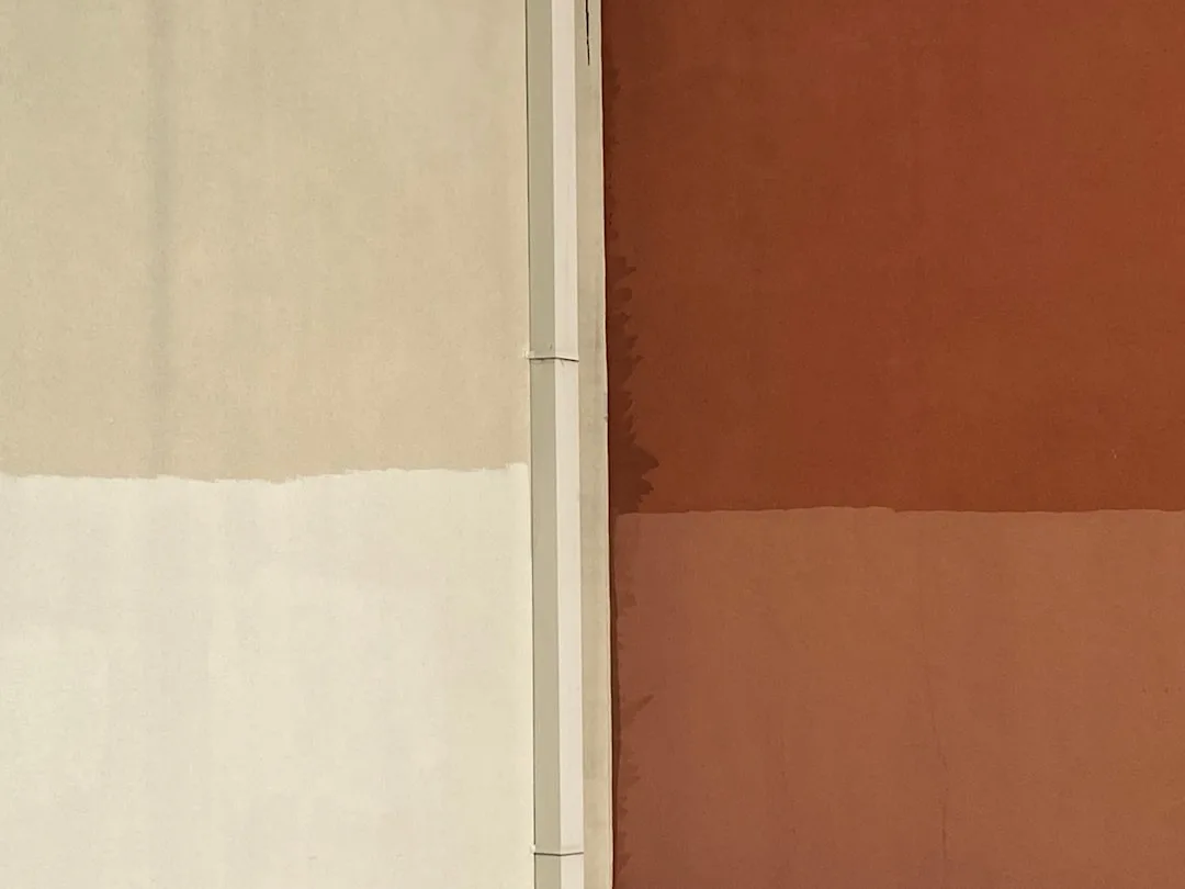 Two-tone wall paint split showing exact horizontal dividing line between terracotta and lighter shade on building exteri