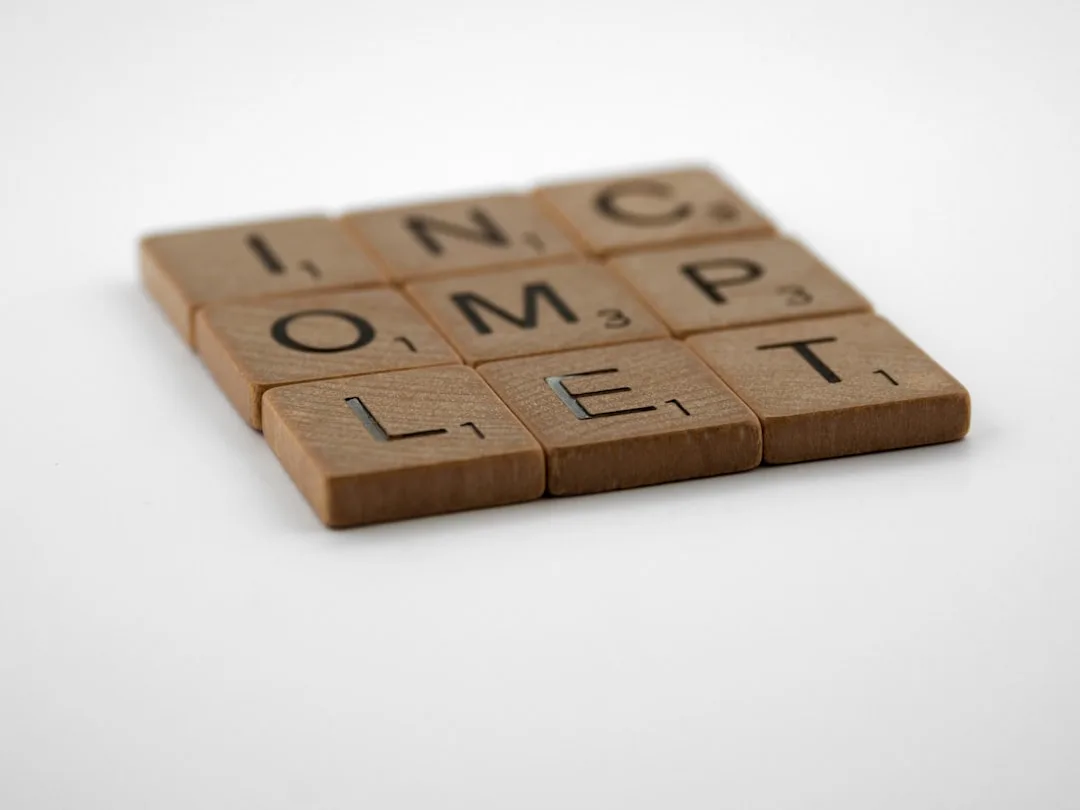 Scrabble tiles spelling INCOMPLETE on white background representing tentative color decisions in bathroom design
