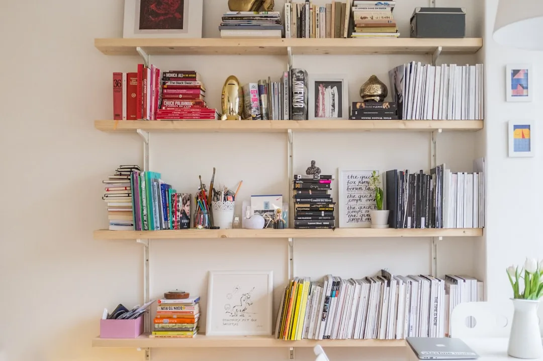 Wall-mounted wooden shelves filled with books, magazines, and decorative objects in a home office organization setup