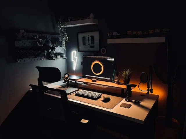 Dark moody home office desk setup with monitor, ke