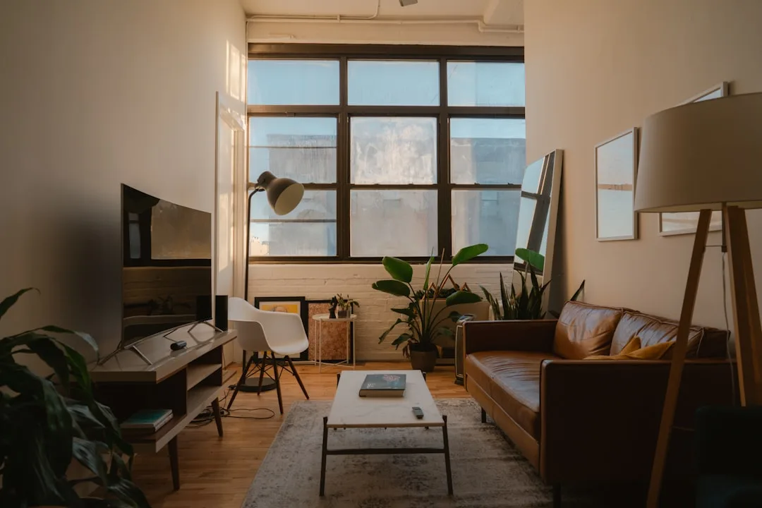 Small apartment living room with brown leather sofa, coffee table, and smart TV arrangement maximizing limited space