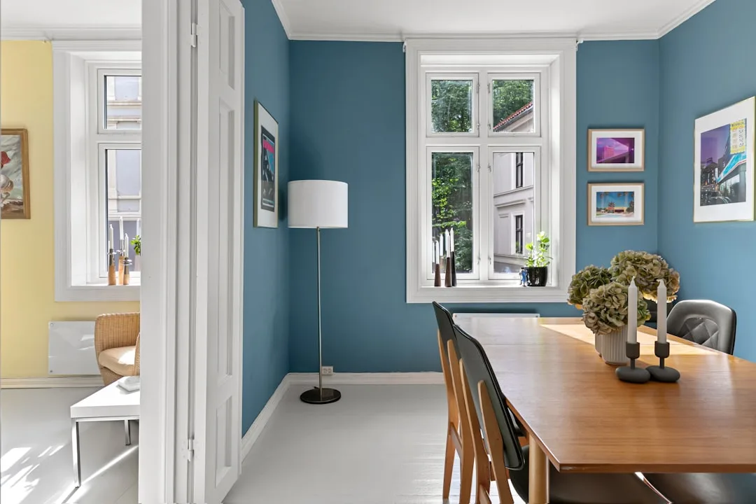 Blue-painted dining room walls with white trim showing how specific paint colors create a spacious, airy feel