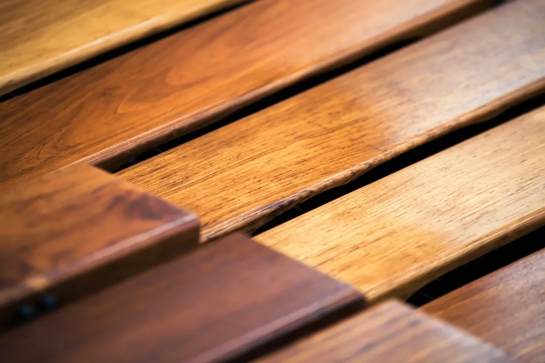 Close-up of polished teak wood slats showing rich grain texture and warm golden-brown tones for outdoor furniture