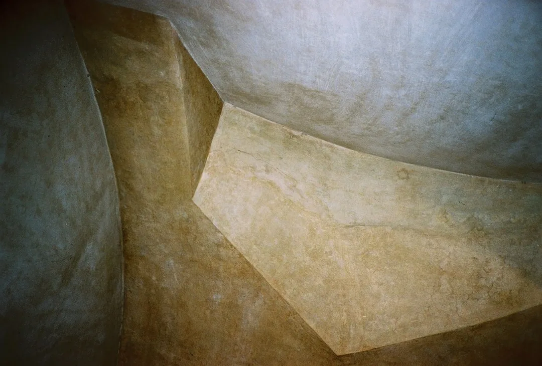 Close-up of plastered concrete interior surfaces with geometric angular planes and warm earthy tones