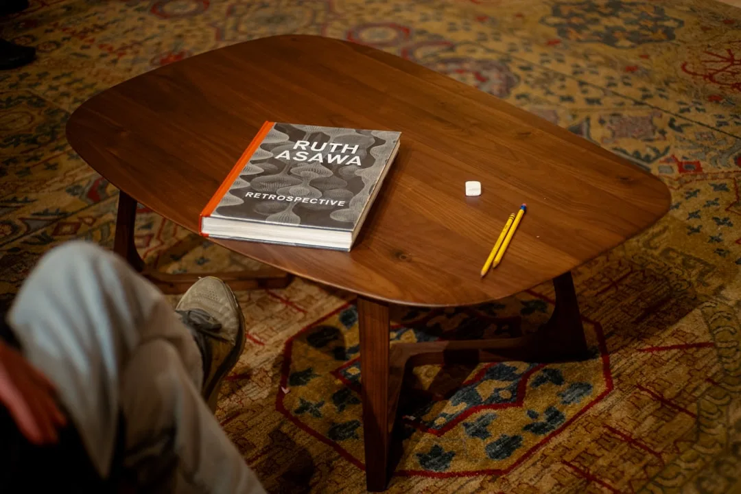 Oval mid-century modern walnut coffee table on patterned rug showing organic shape footprint in living room