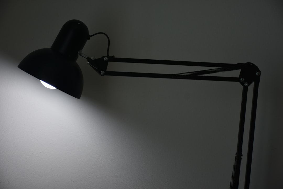Black adjustable desk lamp illuminating a home office wall