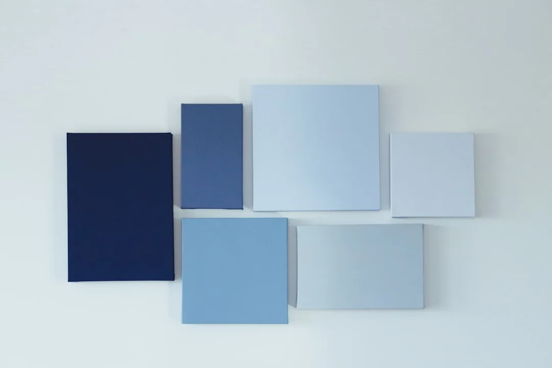 Blue paint color swatches arranged on white surface showing range from navy to light blue for paint sample testing