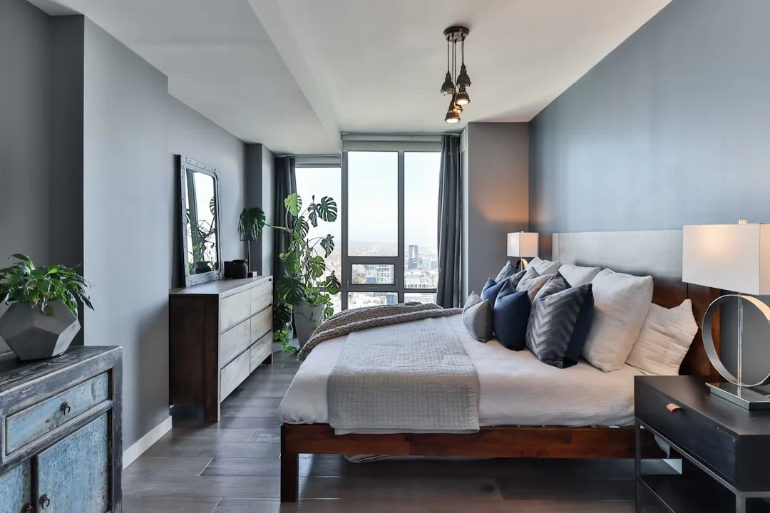 Modern bedroom with gray walls, navy and white bedding, wood furniture demonstrating the 60-30-10 color rule