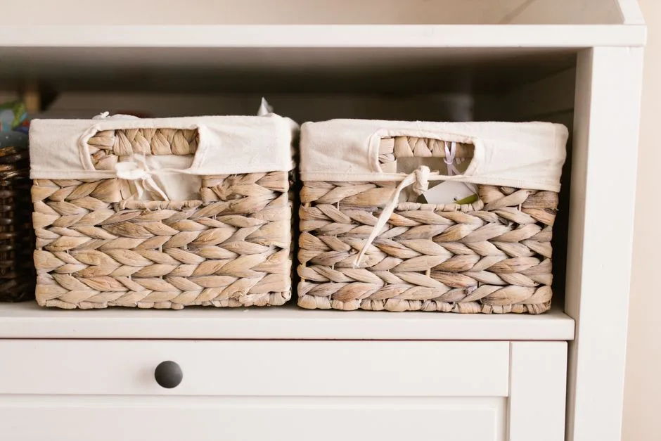 Two woven hyacinth storage baskets with white fabric liners on a white shelf for linen closet organization