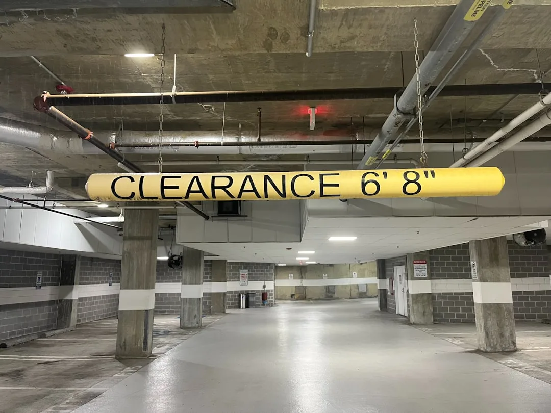 Yellow clearance bar in parking garage showing 6 feet 8 inches height restriction