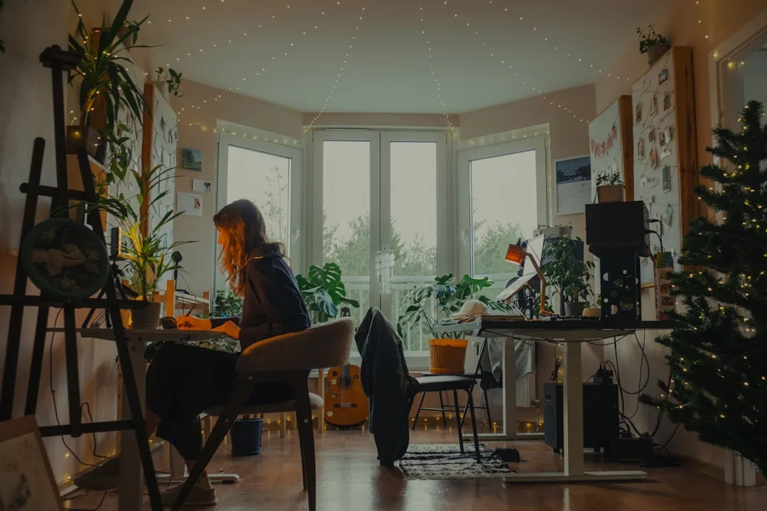 Cozy studio workspace with Christmas tree, fairy lights, and plants showing balanced holiday decor in small space