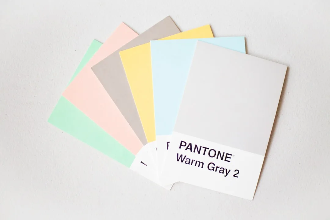 Pantone Warm Gray 2 color swatch fanned with pastel mint, pink, taupe, yellow, and blue swatches for 2026 color trends