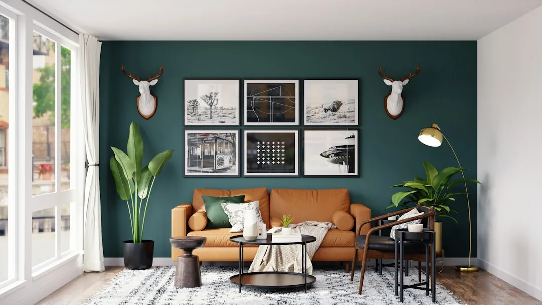Living room with dark teal accent wall, tan leather sofa, and light wood floors demonstrating strong value contrast in i