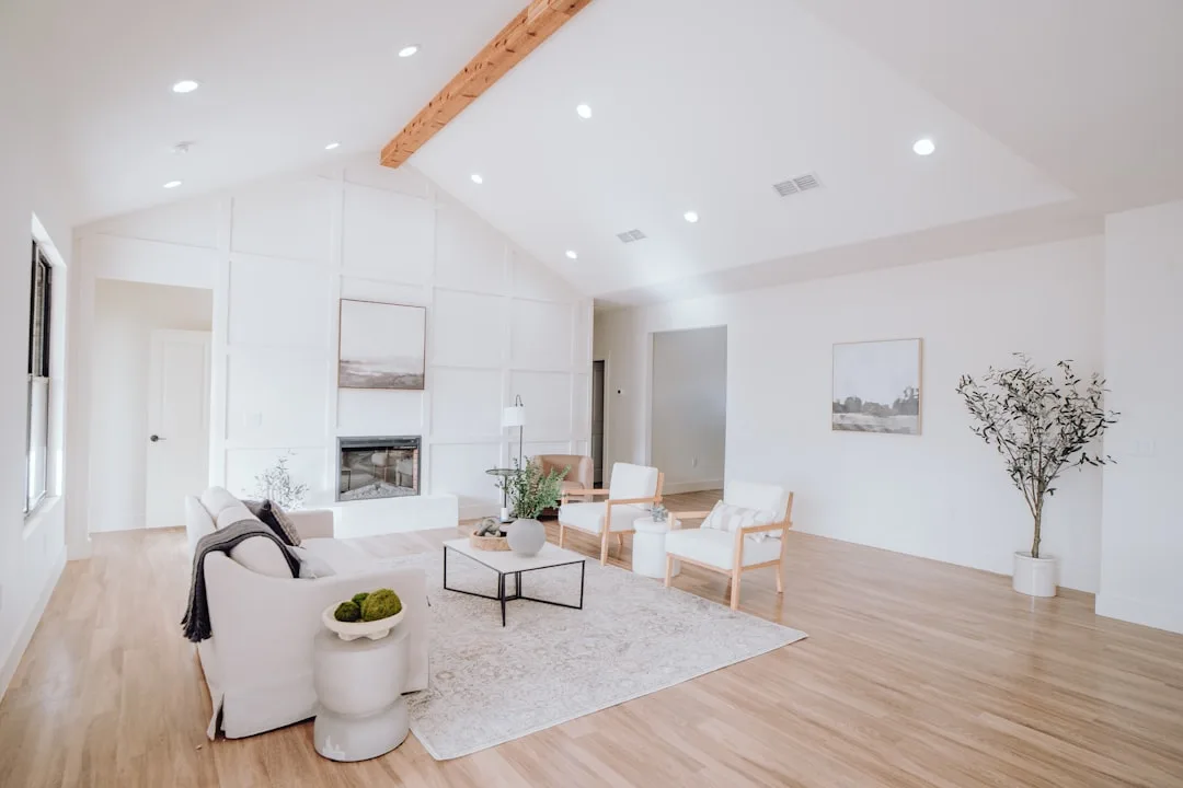 Minimalist white living room with floating furniture arrangement featuring sofa, chairs and coffee table centered on rug