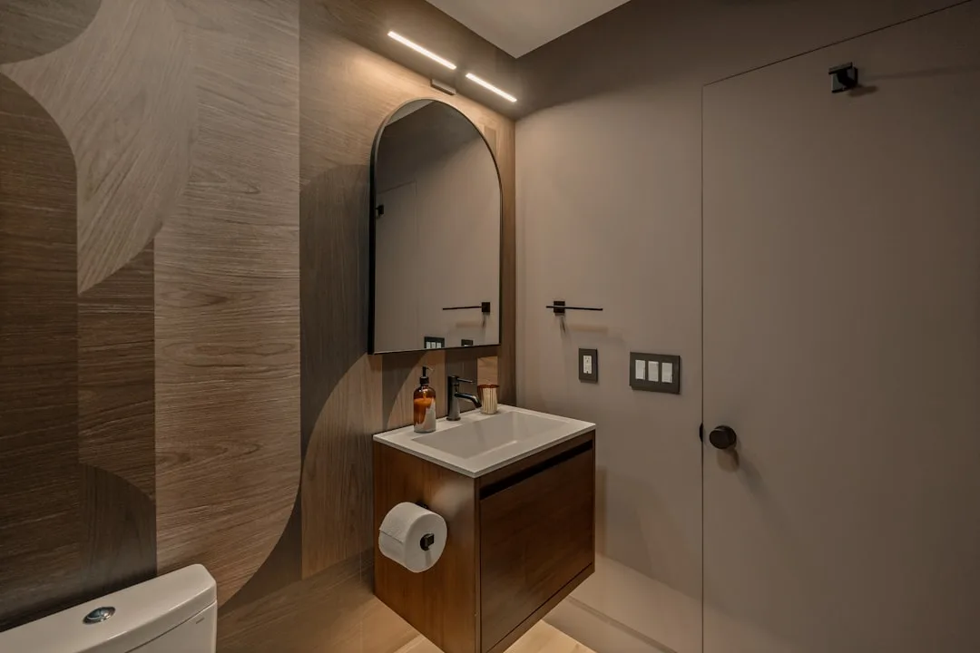 Modern powder room layout with floating vanity, arched mirror, wood accent wall, and compact footprint design