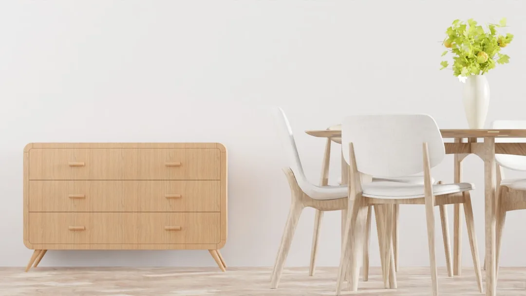 Scandinavian dining room with wooden dresser, light wood chairs, round table and white vase with green flowers