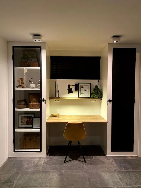 Built-in floating desk nook with wood surface, yellow chair, and shelving unit in small home office space