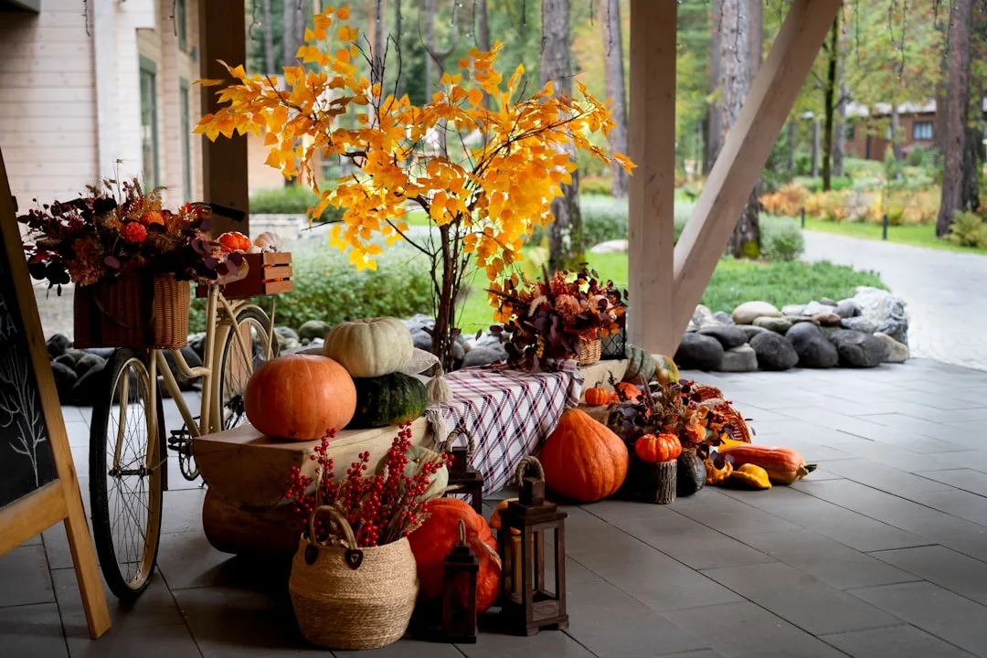 Fall entry decor with pumpkins, orange autumn tree, wicker baskets, and vintage bicycle on a covered porch