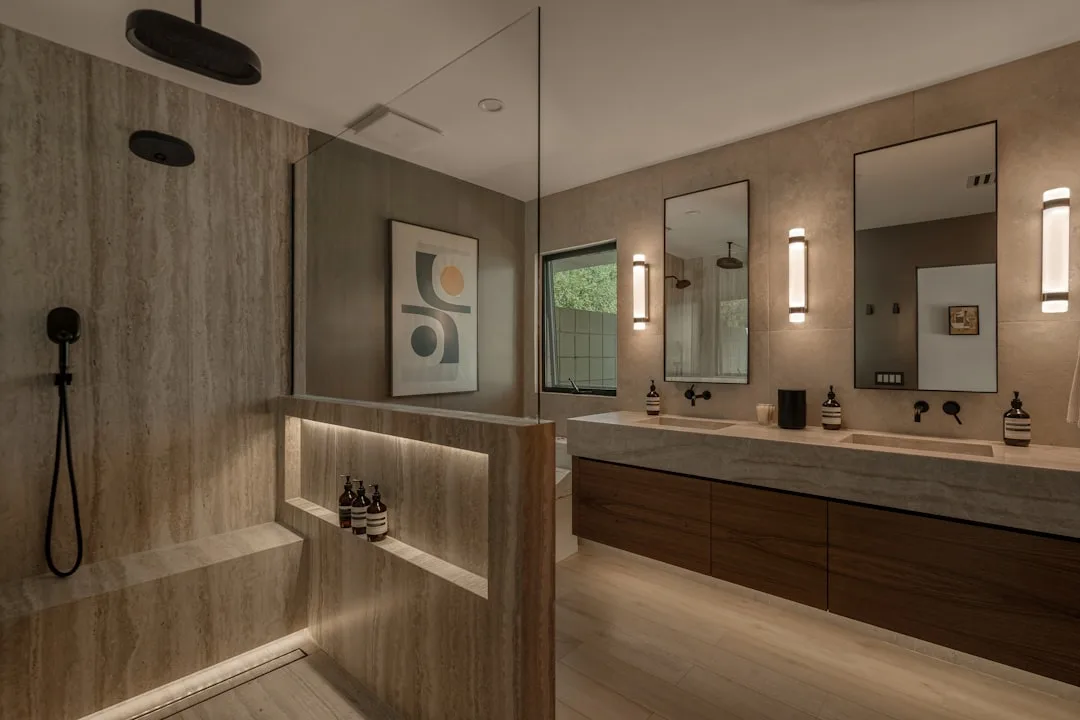Luxury bathroom shower niche with LED underlighting at bench height, travertine tile walls and built-in product shelf