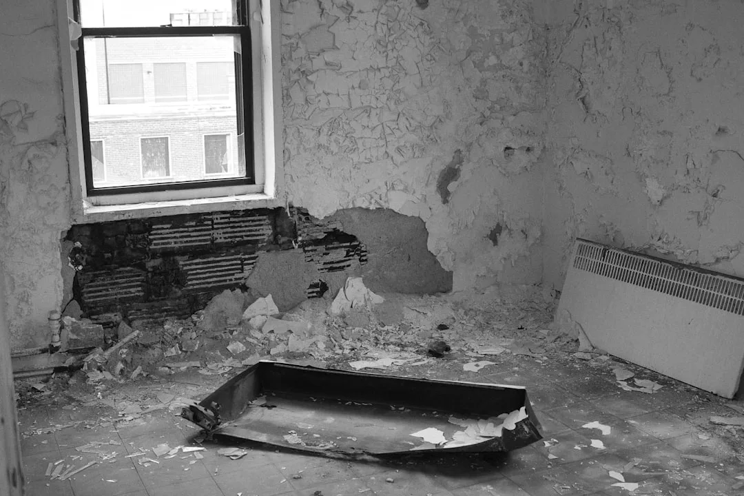 Abandoned room with severe water damage, peeling walls, collapsed plaster and debris showing tanking failure consequence