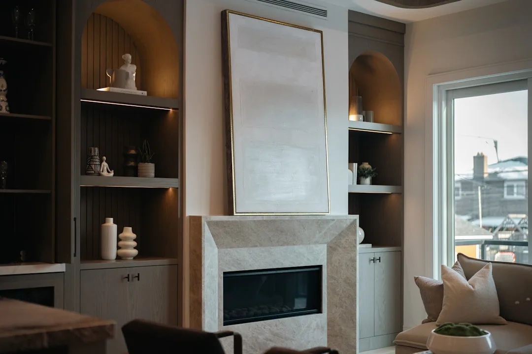 Built-in fireplace alcove with marble surround, flanking shelving units and arched niches in a modern living room