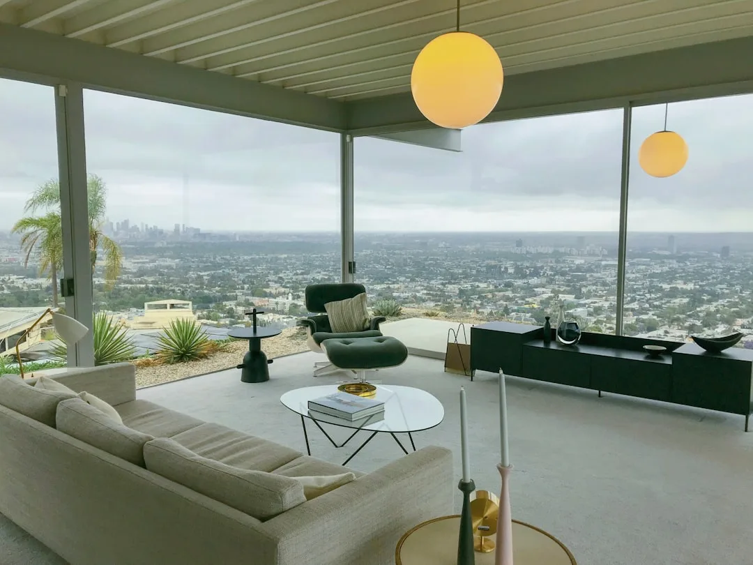 Mid-century modern lounge chair at 45-degree angle in living room with panoramic city view and globe pendant lights