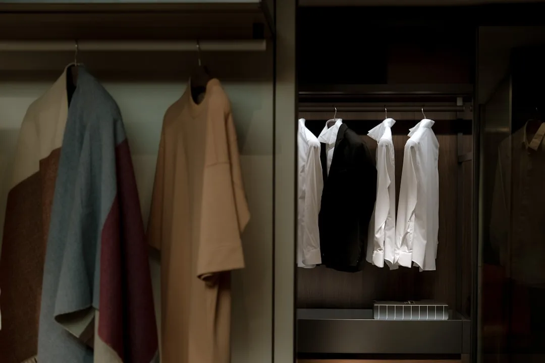 Organized coat closet with hanging garments including white shirts and coats on wooden wardrobe rods