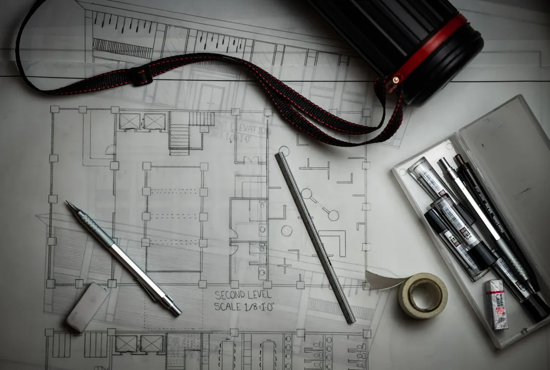 Architectural floor plan blueprint showing second level scale layout with drafting tools, pens, and eraser