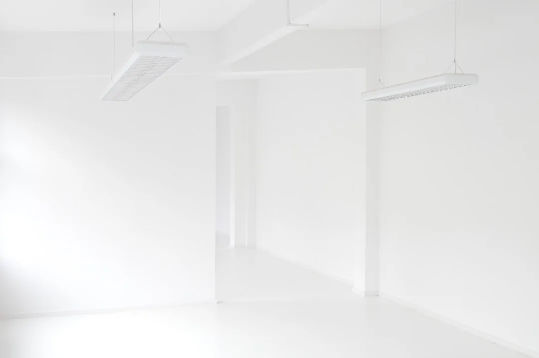 Bright white empty room with cool north-facing light and suspended white pendant lights showing pure white LRV interior