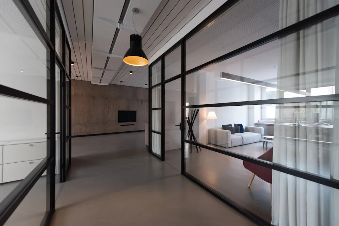 Modern open-plan interior with glass partition walls dividing living zones by use frequency and function