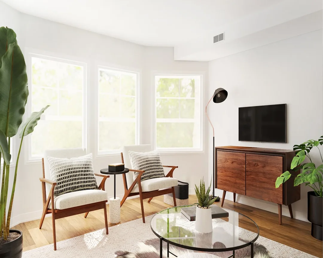 Mid-century modern living room with two accent chairs and TV credenza creating distinct visual zones with natural light