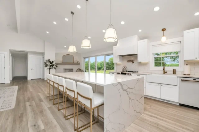 Large white kitchen with marble waterfall island,