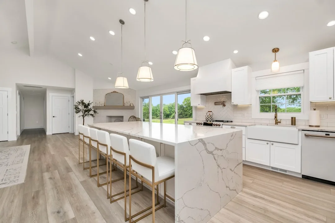 Large white kitchen with marble waterfall island,