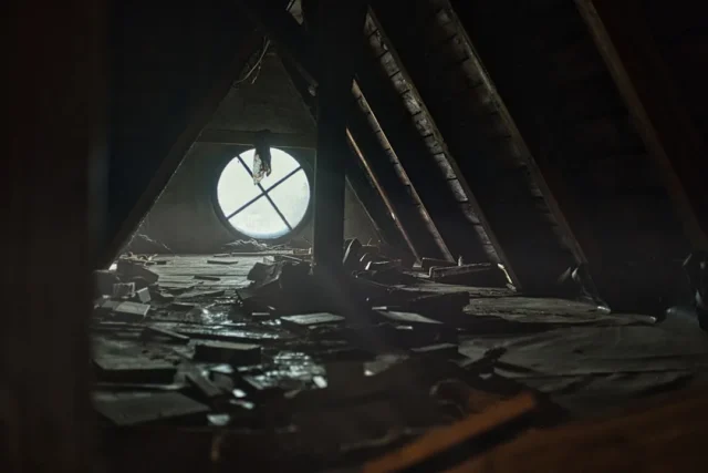 Dark abandoned attic interior with low sloped raft