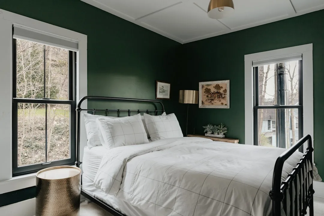 Dark green moody bedroom with black iron bed frame