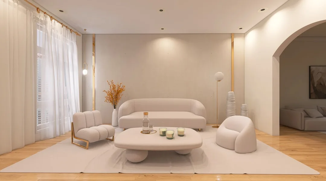 Warm white living room with cream sofa, bouclé chairs, round coffee table, and gold accents on light wood floors